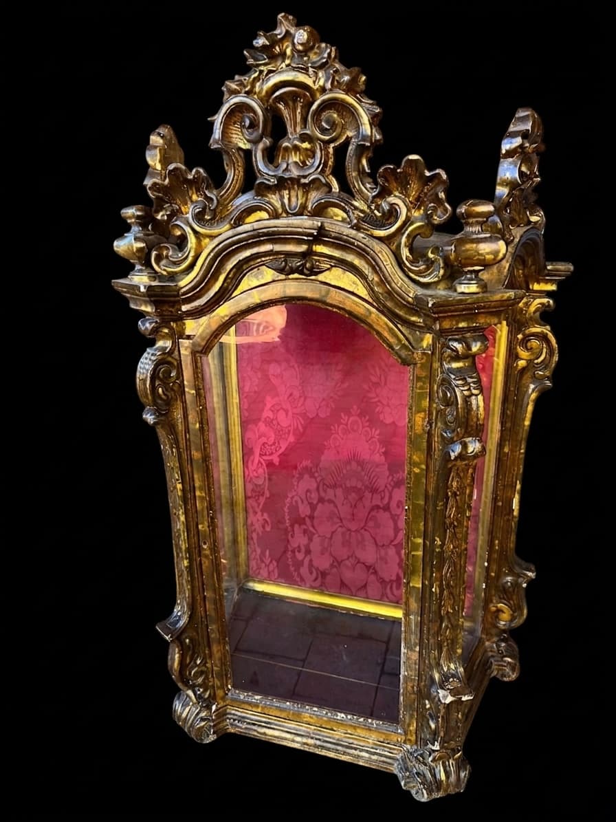 Vitrina antigua dorada de estilo barroco con interior de damasco rojo y tallas ornamentadas.